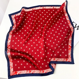 Detailed view of red silk square scarf with blue paisley borders and floral patterns