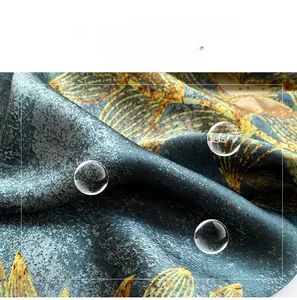 Detailed view of silk-like beach scarf with yellow leaf patterns on blue-grey fabric