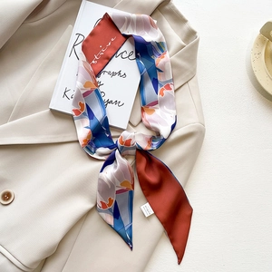 Close-up of a decorative long silk scarf with geometric patterns and 'strive' text