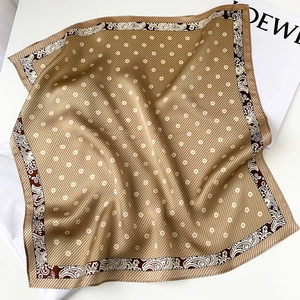 Detail of silk square scarf featuring gold paisley patterns and white floral prints