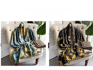 Detailed view of grey-blue and black silk-like scarves with elegant golden leaf patterns