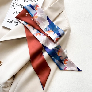 Close-up of printed silk twilly scarf styled on a beige blazer with floral patterns