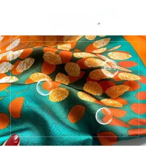 Macro shot of peacock green faux silk scarf with orange leaf pattern and soft texture