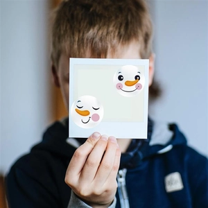 Child holding snowman holiday stickers with polaroid style borders for gift decoration