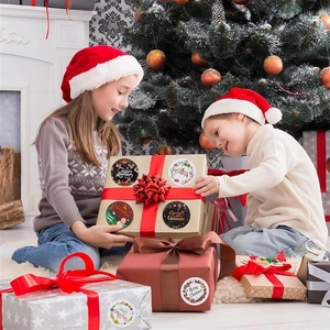Children decorating gift boxes with festive Christmas wreath and snowman roll stickers