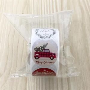 Close-up of a roll of round Christmas stickers with red truck and snowflake designs