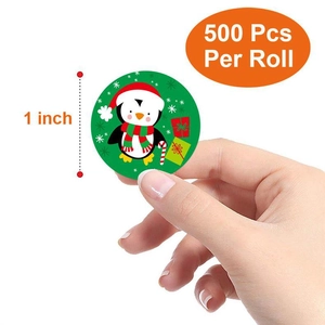 Detail of 1-inch Christmas penguin sticker being held to show size and quality