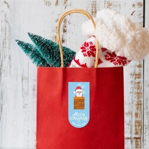 Vue détaillée d'un autocollant Père Noël sur un sac cadeau en papier rouge