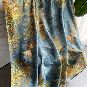 Detail of silk-like beach shawl featuring golden butterfly prints on grey-blue fabric