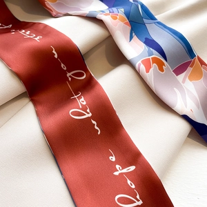 Detail of silk-like neckerchief with elegant prints and artistic lettering on beige fabric