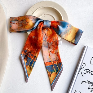 Close-up of artistic printed silk twilly tied in a bow on a white ceramic plate