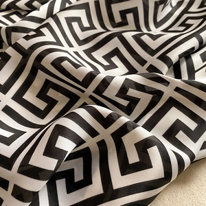 Detailed close-up of geometric Greek key pattern on lightweight silky fabric