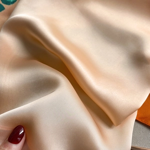 Close-up of elegant champagne silk scarf fabric with a smooth glossy texture and soft drapes