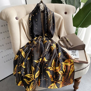 Elegant black silk scarf with golden leaf patterns and luxurious satin finish long wrap