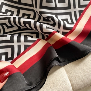 Close-up of geometric Greek key silk scarf with red and beige striped border