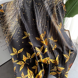 Detail of silk-like satin scarf featuring gold leaf patterns on a black background