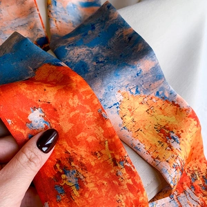 Detail of the abstract oil painting pattern on a silk scarf with vibrant orange and blue