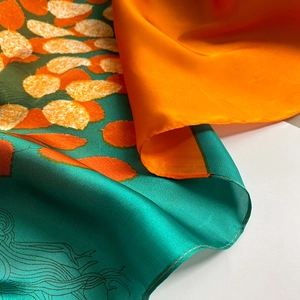 Detail of silk-like floral scarf showing vibrant orange leaf patterns and teal texture