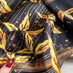 Detail of silk-like beach scarf fabric with elegant gold leaf patterns on black