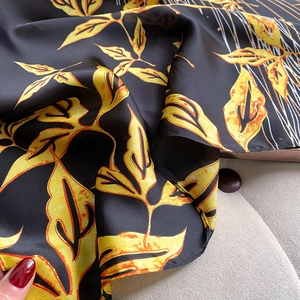 Detailed close-up of high-quality silk-like fabric with elegant yellow leaf print patterns