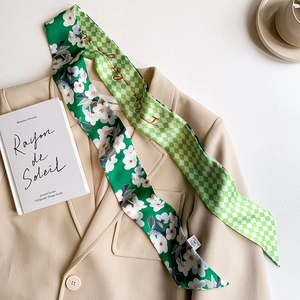 Detail of green floral and checkerboard twilly scarf styled on a beige blazer