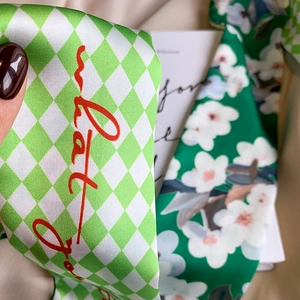 Detail of silk scarf with green plaid and floral patterns, featuring red handwritten text