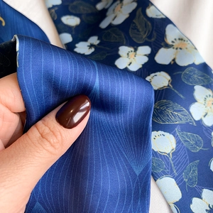 Macro shot showing the smooth twill texture and floral print of this navy silk scarf