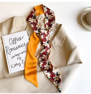 Detail of floral silk twilly scarf styled on a beige blazer with professional aesthetic