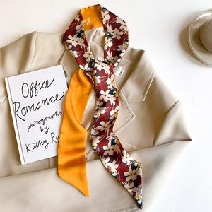 Elegant French twilly silk scarf with floral and orange patterns on a beige blazer