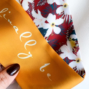 Detailed shot of orange satin ribbon with floral print and handwritten text