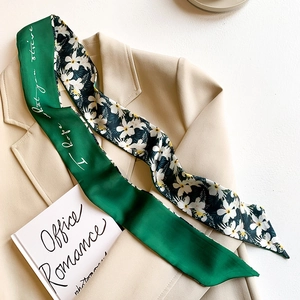 Detail of elegant French style narrow silk scarf with floral print and script on suit