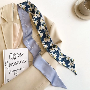 Detail of a dual-sided lavender and navy silk scarf on a beige blazer with a coffee cup