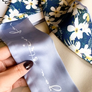Detail of silk twilly scarf with tropical toucan print and elegant lilac script design