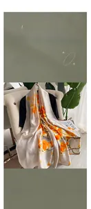Detailed texture of ivory silk satin scarf featuring vibrant orange floral fruit patterns