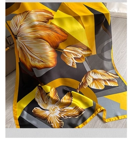Close-up of elegant silk scarf featuring yellow tulip patterns and modern geometric stripes