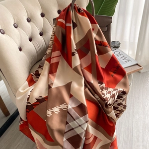 Elegant silk-feel beach scarf with red and coffee houndstooth patterns on a sofa