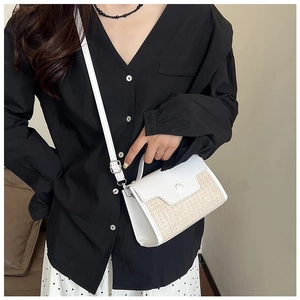 Détail du sac à bandoulière en paille et cuir blanc porté sur une chemise noire