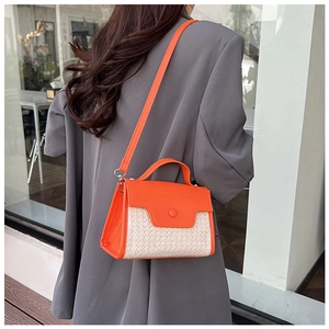 Détail d'un sac bandoulière en similicuir orange et paille tressée avec boucle ronde
