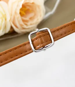 Détail de la bandoulière en cuir PU marron avec boucle argentée et surpiqûres