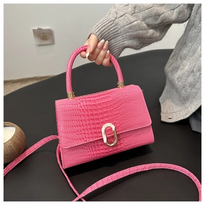 Detail of bright pink crocodile pattern handbag with gold clasp and elegant handle