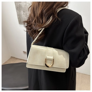 Détail d'un sac baguette en cuir brillant blanc cassé avec une boucle en métal doré en U