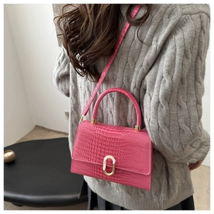 Fashionable magenta crocodile pattern handbag styled with grey sweater on a model