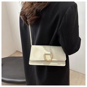Détail d'un sac à bandoulière en cuir blanc crème avec boucle fer à cheval dorée et sangle