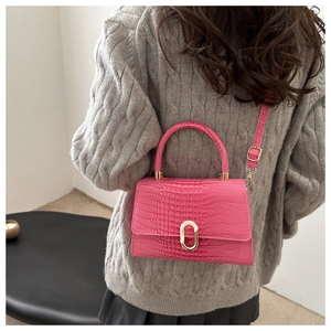Close-up of rose red crocodile pattern handbag with elegant gold oval metal buckle