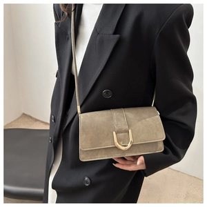 Sac bandoulière rétro kaki mat avec boucle fer à cheval dorée porté par un modèle
