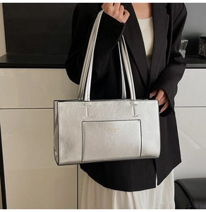 Detailed view of silver metallic tote bag featuring fine faux leather texture and outer pocket