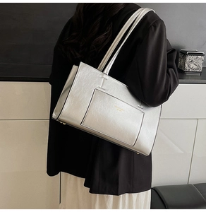 Detail of silver metallic tote bag featuring gold embossed text on the front pocket