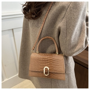 Detail of vintage crocodile pattern handbag in khaki with elegant gold metal buckle
