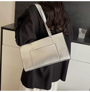 Detail of silver metallic tote bag with front pocket shown on shoulder by a model