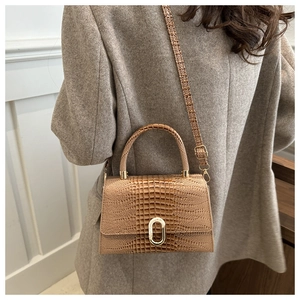 Detail of khaki crocodile pattern handbag with gold U-shaped buckle and crossbody strap